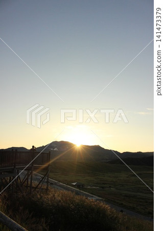 A scene of the sunrise over Kusasenrigahama in Aso City, Kumamoto Prefecture, featuring a vast grassland and pond bathed in the morning sun, and Mount Aso Nakadake with its rising plume of smoke. A scene of the sunrise over Kusasenrigahama in Aso City, Kumamoto Prefecture, featuring a vast grassland and pond bathed in the morning sun, and Mount Aso Nakadake with its rising plume of smoke. 141473379