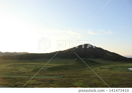 A scene of the sunrise over Kusasenrigahama in Aso City, Kumamoto Prefecture, featuring a vast grassland and pond bathed in the morning sun, and Mount Aso Nakadake with its rising plume of smoke. A scene of the sunrise over Kusasenrigahama in Aso City, Kumamoto Prefecture, featuring a vast grassland and pond bathed in the morning sun, and Mount Aso Nakadake with its rising plume of smoke. 141473410