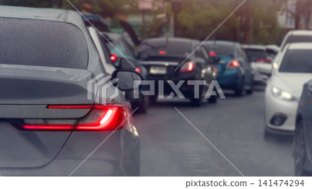 Rear view perspective of cars stuck in a traffic jam on an urban asphalt road. During the daytime emphasizing the busy commute. Traffic jam is visible as a curved line in the distance ahead. Rear view perspective of cars stuck in a traffic jam on an urban asphalt road. During the daytime emphasizing the busy commute. Traffic jam is visible as a curved line in the distance ahead. 141474294