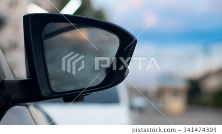 Close up side view of a vehicle's side mirror reflecting traffic on a highway. During a bright day capturing motion and refreshing and cheerful travel experience. Close up side view of a vehicle's side mirror reflecting traffic on a highway. During a bright day capturing motion and refreshing and cheerful travel experience. 141474303