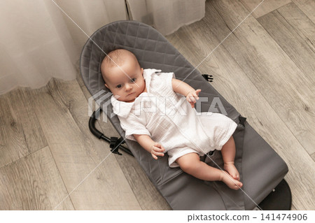 Newborn enjoys quiet time in a soft bouncer chair Newborn enjoys quiet time in a soft bouncer chair 141474906