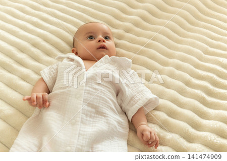 Baby relaxes on a fluffy blanket while looking up in wonder Baby relaxes on a fluffy blanket while looking up in wonder 141474909