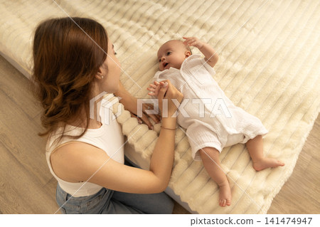 Mom enjoys a tender moment with her baby on a soft blanket Mom enjoys a tender moment with her baby on a soft blanket 141474947