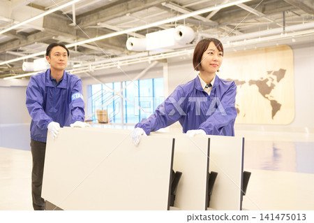 Two staff members carrying in folding tables during venue setup. Two staff members carrying in folding tables during venue setup. 141475013