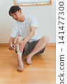 一位四十多歲的男子用T型剃刀刮腿毛。 141477300