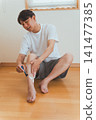 一名四十多歲的男子正在使用T型剃刀去除腿毛。 141477385