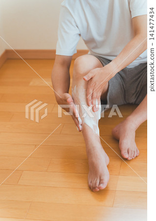 一名男子正在小腿上塗抹刮鬍膏。 一名男子正在小腿上塗抹刮鬍膏。 141477434