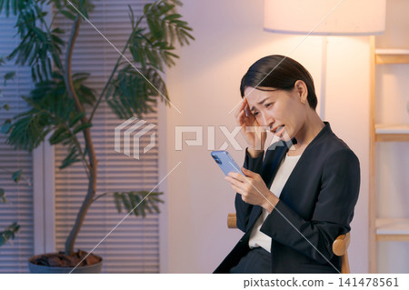 A woman in a suit looking at her smartphone and worrying A woman in a suit looking at her smartphone and worrying 141478561