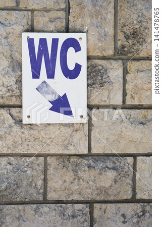 Public WC toilet sign on stone wall 141478765