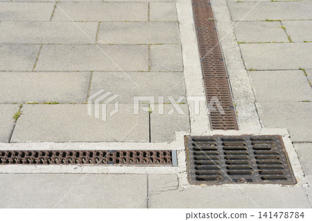 Rusty storm drain grate system on stone pavement Rusty storm drain grate system on stone pavement 141478784