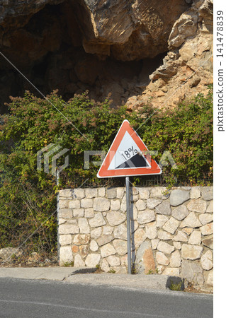 Steep hill downwards road sign 18 percent incline by cliff Steep hill downwards road sign 18 percent incline by cliff 141478839
