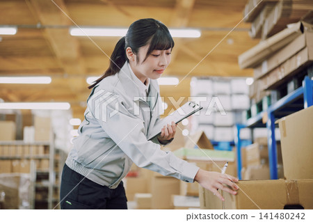 一名穿著工作服的女士在倉庫管理庫存 141480242