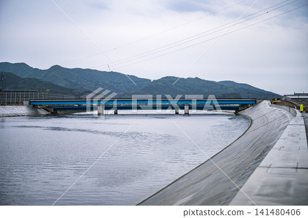 The concrete seawalls along the river, newly constructed after the Great East Japan Earthquake, and the scenery of blue bridges and mountain ranges. The concrete seawalls along the river, newly constructed after the Great East Japan Earthquake, and the scenery of blue bridges and mountain ranges. 141480406