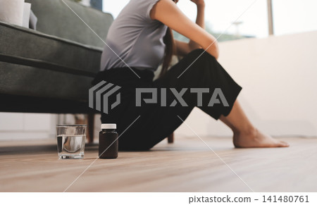 Young Asian woman sitting in bed and holding her head in pain with headache, feeling depressed and suffering 141480761
