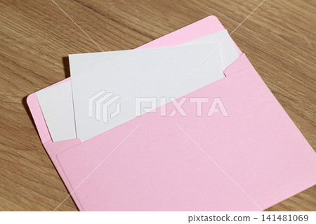 Pink envelope with blank white cards on a wooden table surface Pink envelope with blank white cards on a wooden table surface 141481069