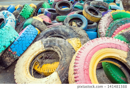 Pile of old multicolored car tires dug in playgrounds. Multicolor used tires. various sizes colored tires. Pile of old multicolored car tires dug in playgrounds. Multicolor used tires. various sizes colored tires. 141481388