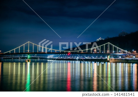 Foot bridge in Kiev at night. Beautiful bridge over the river with LED lighting at night. Ukraine. Foot bridge in Kiev at night. Beautiful bridge over the river with LED lighting at night. Ukraine. 141481541
