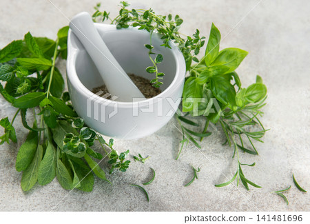 Mortar and pestle grinding fresh herbs for wellness Mortar and pestle grinding fresh herbs for wellness 141481696