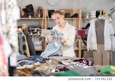 Selective teen girl choosing jean pantaloons in clothing store Selective teen girl choosing jean pantaloons in clothing store 141482162