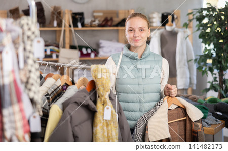 While shopping, teen girl browsing goods items and choose elect down jacket in store While shopping, teen girl browsing goods items and choose elect down jacket in store 141482173