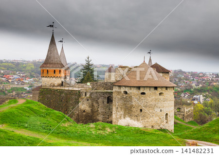 Old Kamianets-Podilskyi Castle under a cloudy grey sky. The fortress located among the picturesque nature in the historic city of Kamianets-Podilskyi, Ukraine Old Kamianets-Podilskyi Castle under a cloudy grey sky. The fortress located among the picturesque nature in the historic city of Kamianets-Podilskyi, Ukraine 141482231