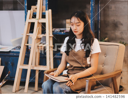 Female artist wears black hat posing near picture indoor the studio Female artist wears black hat posing near picture indoor the studio 141482596
