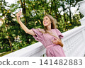 Smiling Woman Taking Selfie On White Balcony Outdoors 141482883