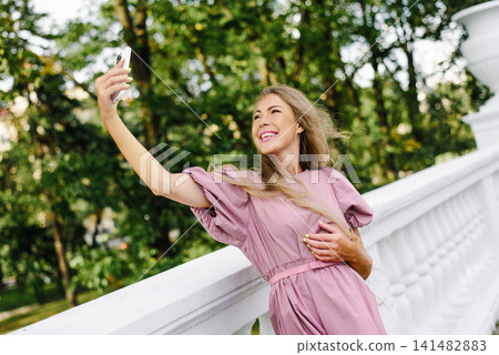 Smiling Woman Taking Selfie On White Balcony Outdoors Smiling Woman Taking Selfie On White Balcony Outdoors 141482883