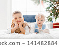 Happy Siblings Lying On Bed Near Christmas Tree 141482884