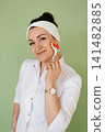Smiling Beauty Specialist Demonstrating Face Roller Tool 141482885