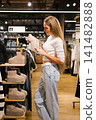 Woman Buyer Examining Beige Boots in Shop 141482888