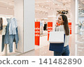 Side View of Woman Looking at Window Display with Shopping Bags 141482890