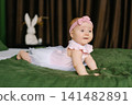 Baby Girl Looking Curious On Green Blanket 141482891
