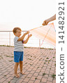 Smiling Boy Holding Bright Kite At Sunset 141482921