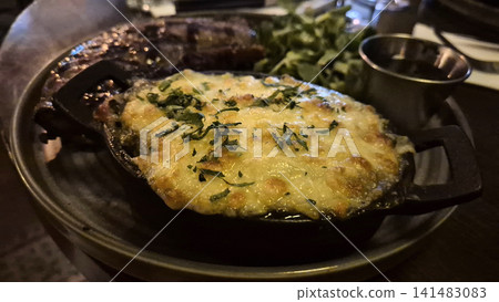 Cheesy baked oyster appetizer in restaurant skillet Cheesy baked oyster appetizer in restaurant skillet 141483083