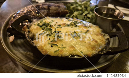 Cheesy baked casserole served in a cast iron skillet Cheesy baked casserole served in a cast iron skillet 141483084