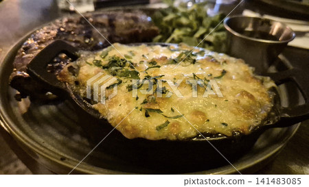 Cheesy baked dish served in sizzling skillet Cheesy baked dish served in sizzling skillet 141483085