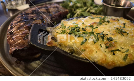 Grilled Steak with Cheesy Baked Topping in Skillet Grilled Steak with Cheesy Baked Topping in Skillet 141483092