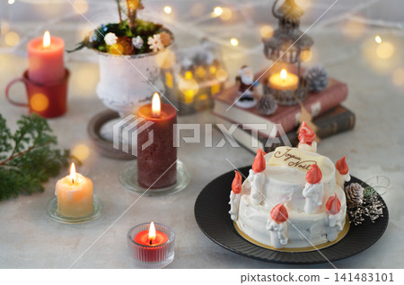聖誕蛋糕被溫暖的燭光和彩色燈環繞。 141483101