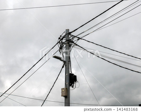 Utility pole with overhead power lines against cloudy sky Utility pole with overhead power lines against cloudy sky 141483168