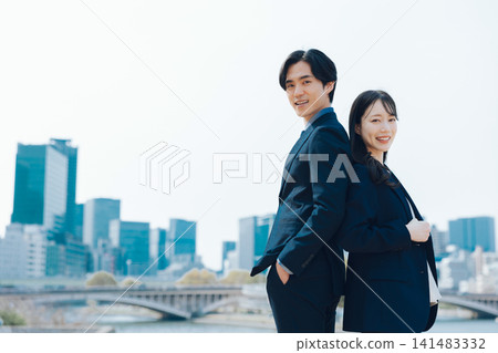 商業場景，畫面中一男一女站在藍天和摩天大樓前。 141483332