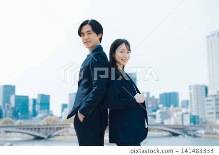 商業場景，畫面中一男一女站在藍天和摩天大樓前。 141483333