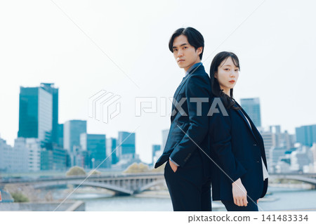 商業場景，畫面中一男一女站在藍天和摩天大樓前。 141483334