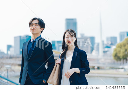 商業場景，畫面中一男一女站在藍天和摩天大樓前。 141483335