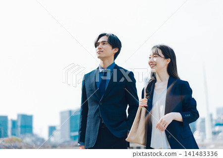 商業場景，畫面中一男一女站在藍天和摩天大樓前。 141483336