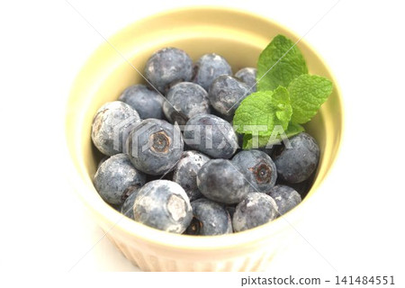 A bowl of harvested frozen blueberries and peppermint leaves 141484551