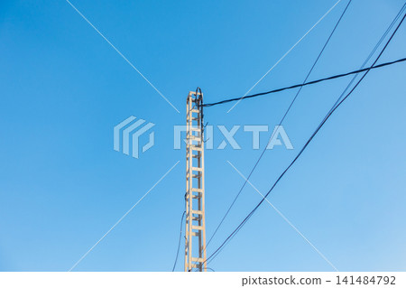 Concrete Utility Pole with Overhead Cables Against Blue Sky Concrete Utility Pole with Overhead Cables Against Blue Sky 141484792
