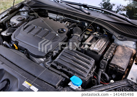 Car engine bay with open hood and battery 141485498