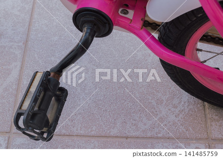 Close up view of worn rusty pedal attached to pink frame of children bicycle on floor for equipment safety checkup and technical service maintenance concept 141485759