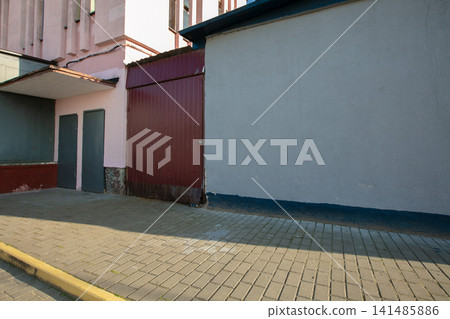 Urban alleyway with textured walls and cobblestone pavement in a quiet neighborhood during daytime hours Urban alleyway with textured walls and cobblestone pavement in a quiet neighborhood during daytime hours 141485886